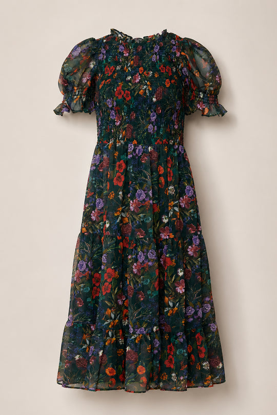 The Cordelia Dress in Evergreen Vivid Meadow by Ivy City Co features a dark, floral print with red, purple, and green tones on a black background. This maternity-friendly puff sleeve dress is designed with short, puffed sleeves, ruffled cuffs, a smocked bodice, and a flowy skirt.