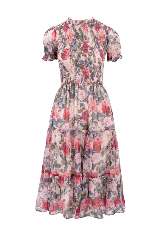 The Cordelia Dress in Pink Bloom by Ivy City Co is a knee-length chiffon dress with short sleeves, a fitted smocked bodice, and a flowing skirt featuring a pink, red, and green floral pattern—perfect for any occasion.