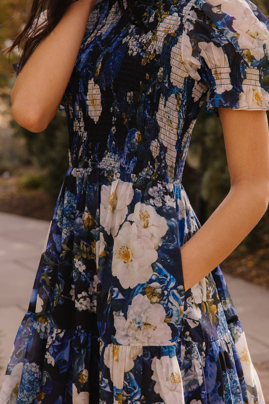 Girl in blue dress in front of trees