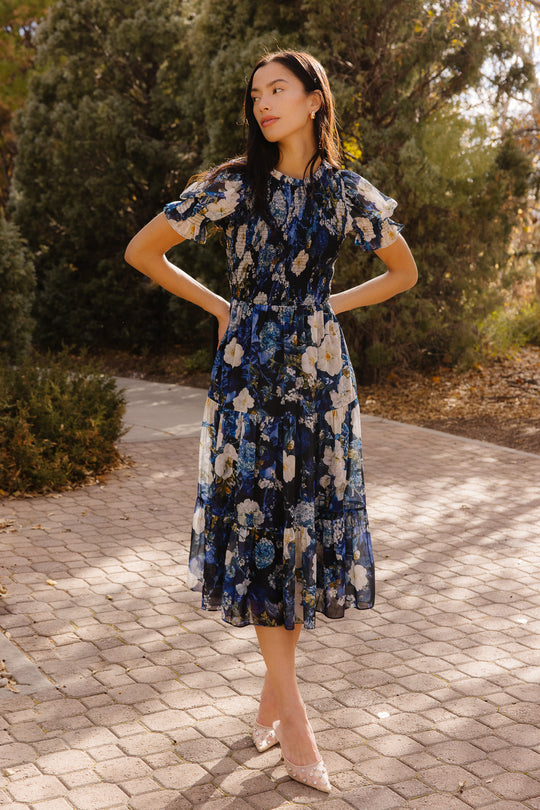 Girl in a blue dress in front of trees