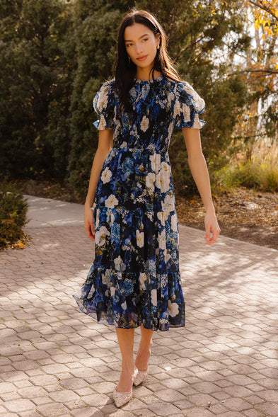 Girl in blue dress in front of trees