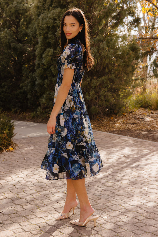 Girl in blue dress in front of trees