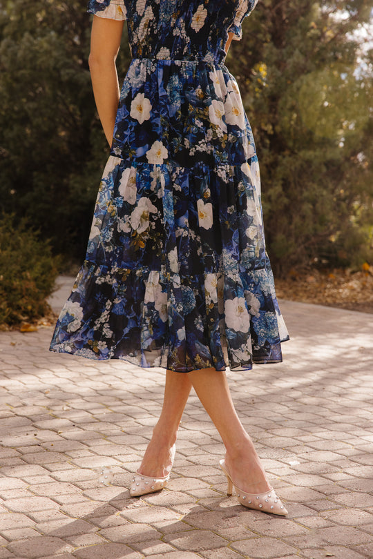 the bottom of a blue dress in front of trees