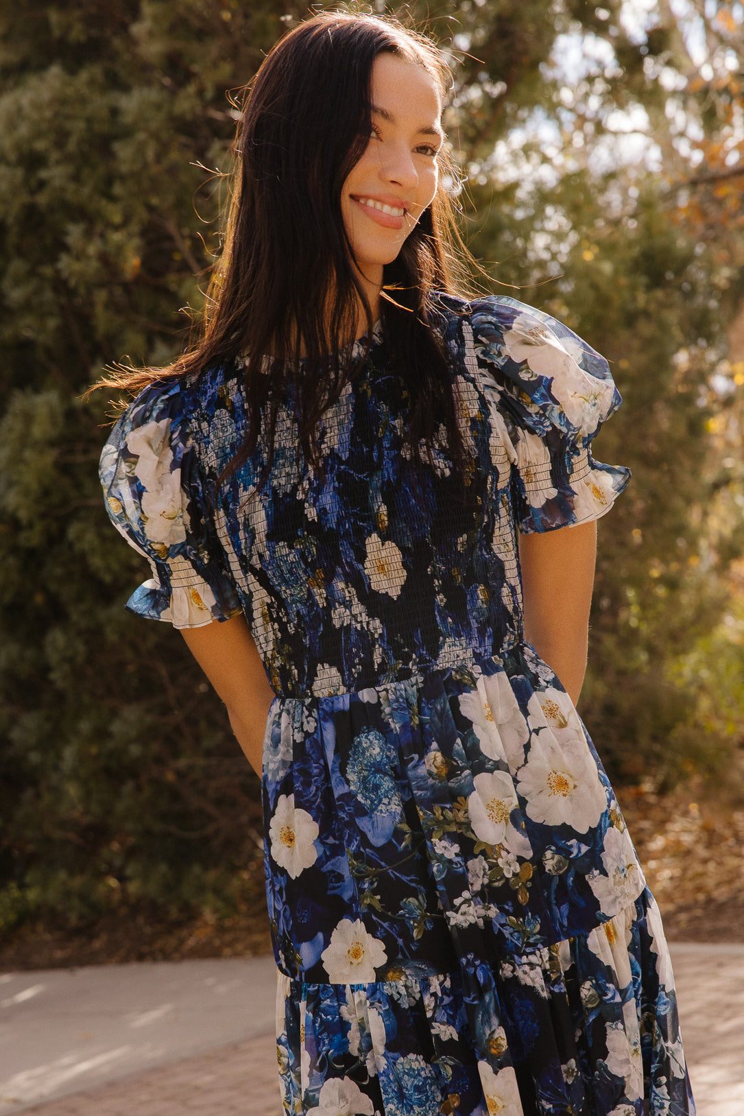 Girl in blue dress in front of trees