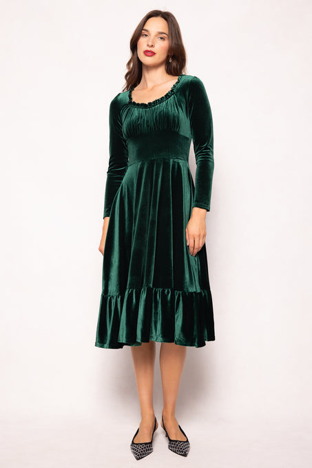 Woman wearing a green velvet dress against a white background