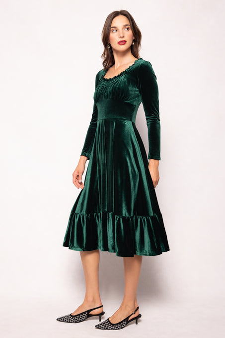 Woman wearing a green velvet dress against a white background