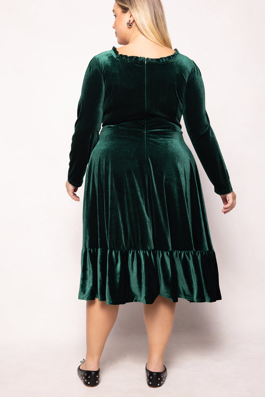 Woman wearing a green velvet dress with a plain background