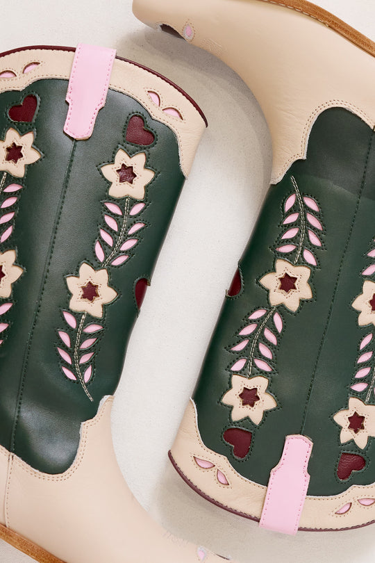Green cowboy boots with floral and heart designs on a white background