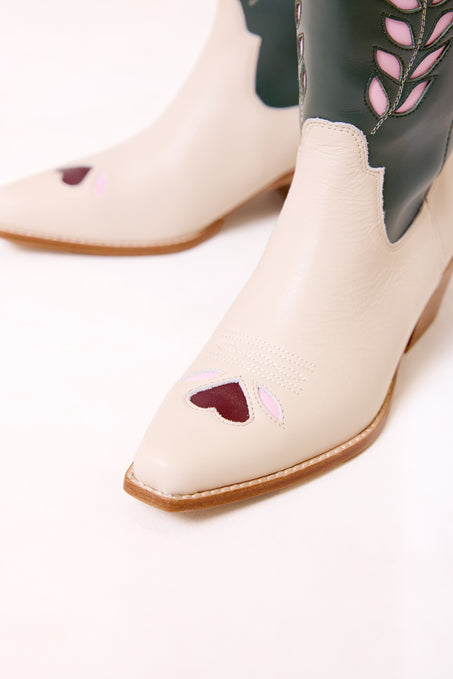 White cowboy boots with heart designs on a white background