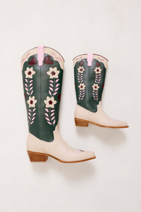 Pair of green and white floral embroidered cowboy boots on a light gray background