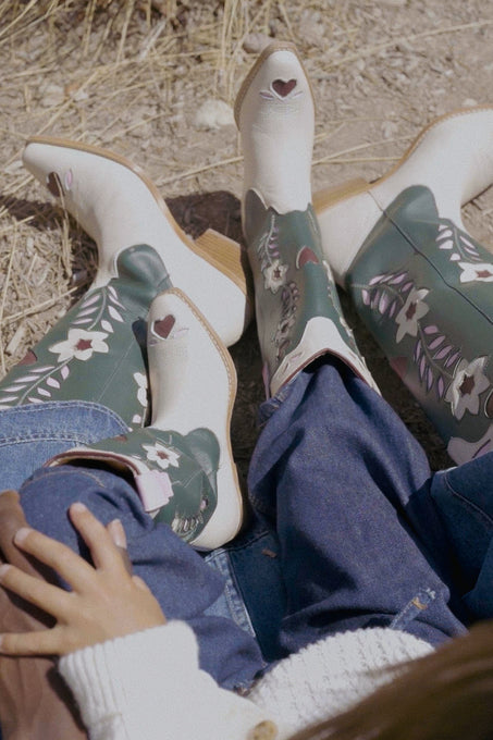 Pair of floral-patterned boots on a person sitting on the ground.