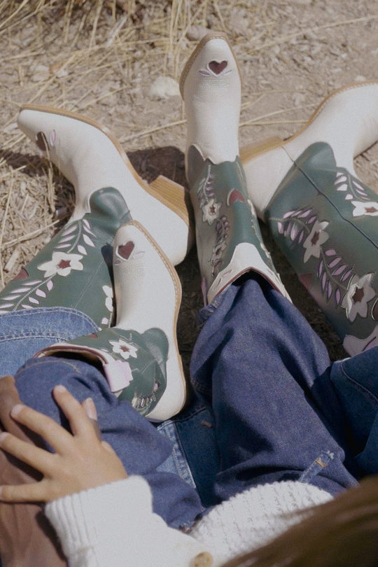 Pair of floral-patterned boots on a person sitting on the ground.