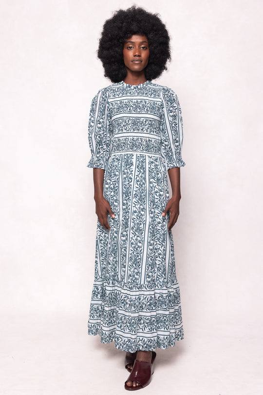 Woman wearing a long floral dress against a white background