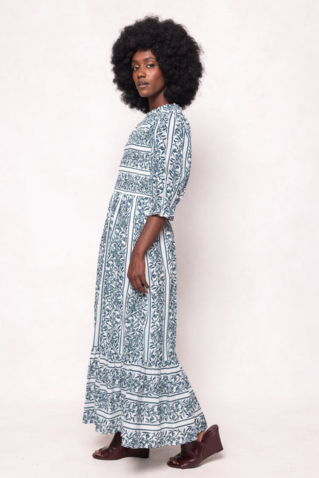 Woman wearing a long, patterned dress against a white background