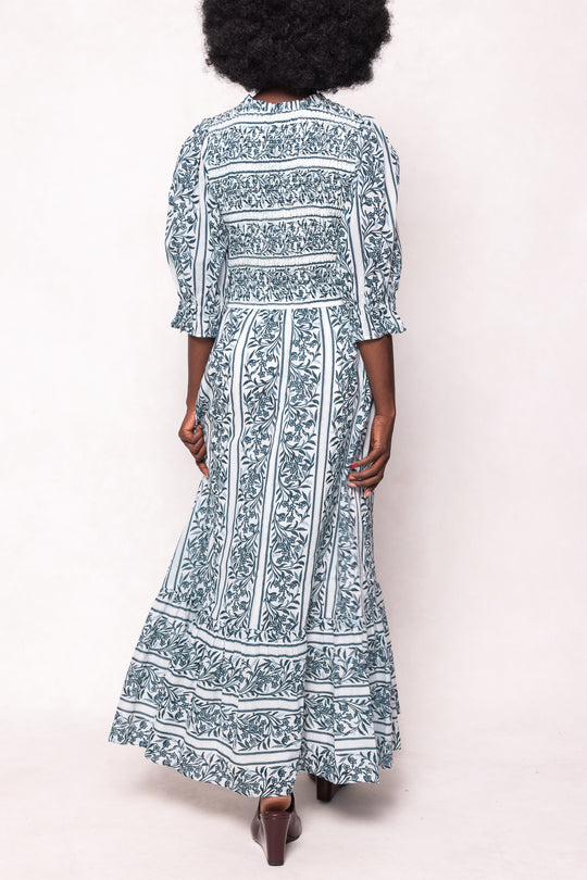 Person wearing a long, patterned dress against a white background