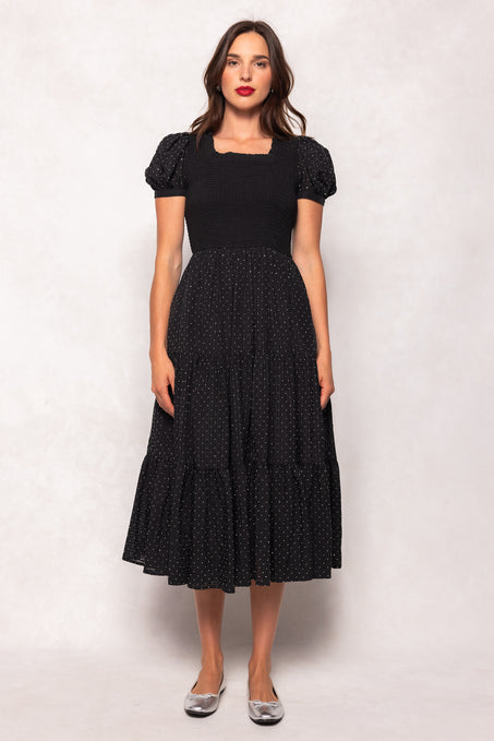 Woman wearing a black dress with white polka dots on a white background