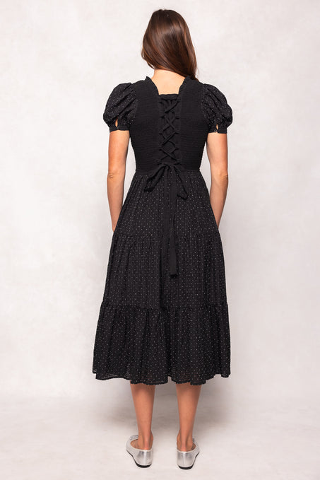 Woman wearing a black dress with white polka dots on a white background