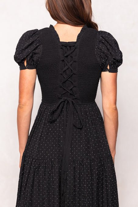 Black dress with puff sleeves and lace-up back on a plain background