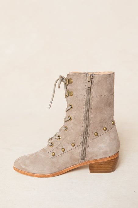 The Mini Darcy Lace Up Studded Boot by Ivy City Co features tan suede, brass eyelets, side zipper, studded heel and base details, a low stacked wooden heel, and a rounded toe for effortless style.