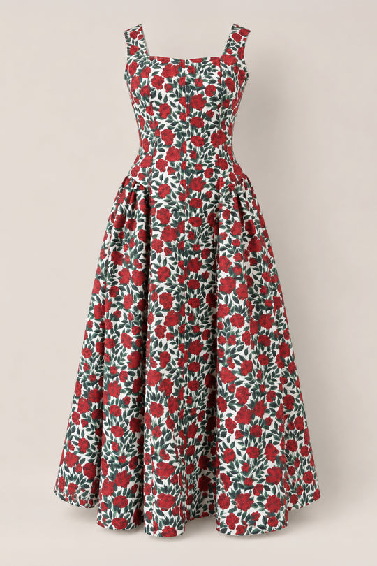 The Edith Dress in Red Roses by Ivy City Co is a sleeveless, ankle-length stretch denim dress with a fitted bodice and flared skirt, featuring a bold red rose floral print on a white background.