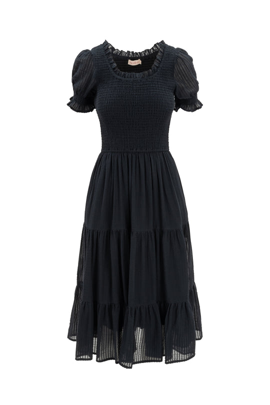 The Ellery Dress in Black by Ivy City Co features a smocked bodice, ruffled neckline, puff sleeves, and a tiered flowy skirt in lightweight fabric—maternity friendly for stylish comfort.