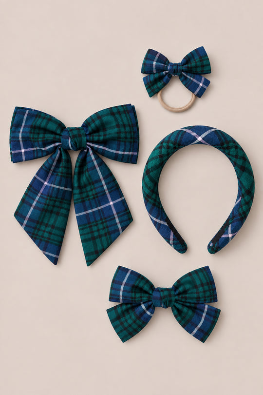 Four hair accessories from Ivy City Co’s “Hair Bows in Emerald Plaid” collection—including an emerald plaid hair bow, a small bow on a hair tie, a headband, and a medium-sized bow—crafted from blue, green, and white tartan fabric and arranged on a neutral backdrop. These pieces are perfect as festive holiday hair accessories or Christmas clips for seasonal styling.