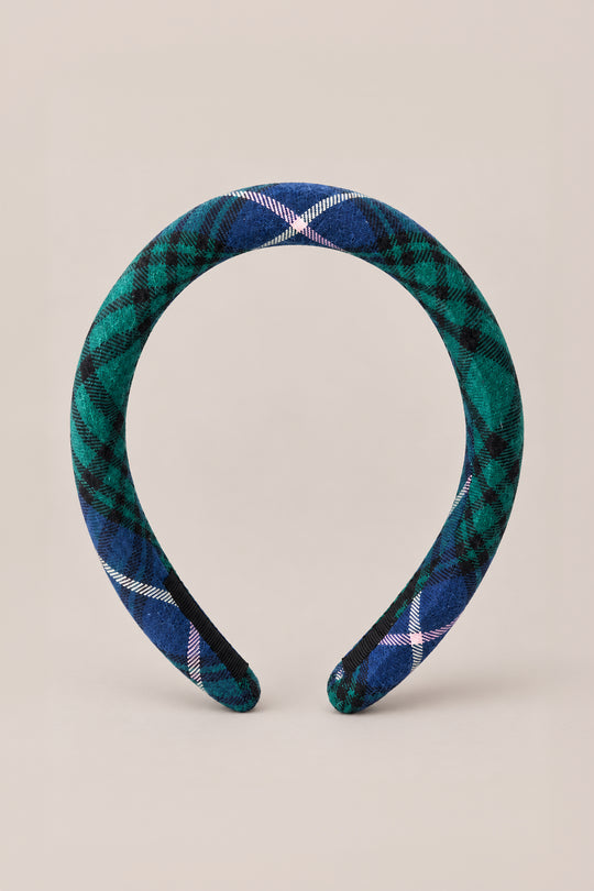A charming holiday hair accessory, the Ivy City Co Hair Bows in Emerald Plaid features a wide, padded headband covered in rich green and blue tones with crisp white accents, beautifully displayed upright on a plain beige background.