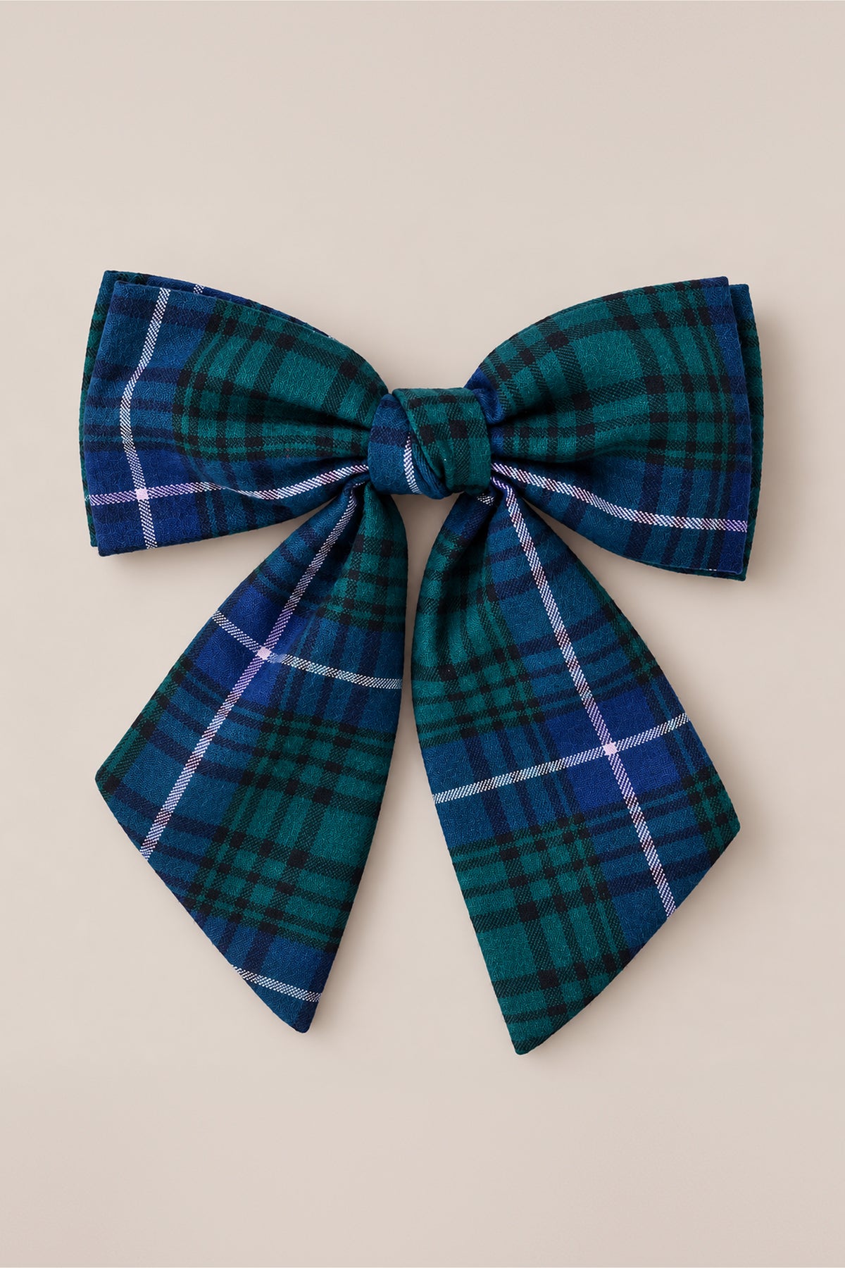 The Ivy City Co Hair Bows in Emerald Plaid showcase a striking combination of green and blue plaid fabric accented with delicate white and purple stripes, set against a plain light beige background—making them an ideal festive holiday hair accessory.