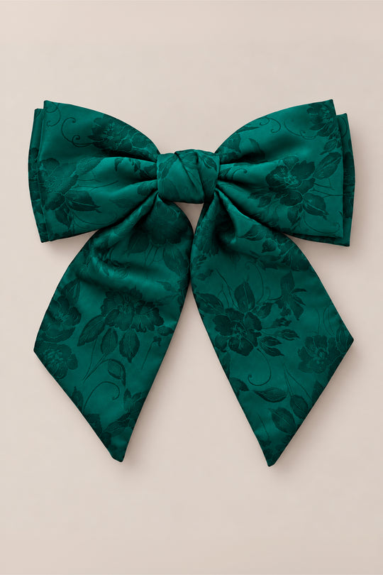 The Hair Bows in Emerald Satin by Ivy City Co feature a large, deep green hue with subtle floral patterns, making them the perfect accessory for girls during Christmas or holiday photo shoots, shown here against a plain beige background.
