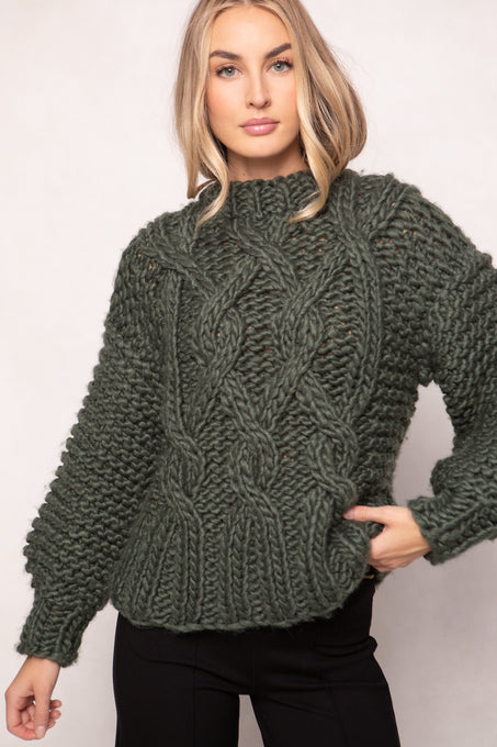 Woman wearing a green knitted sweater against a plain background