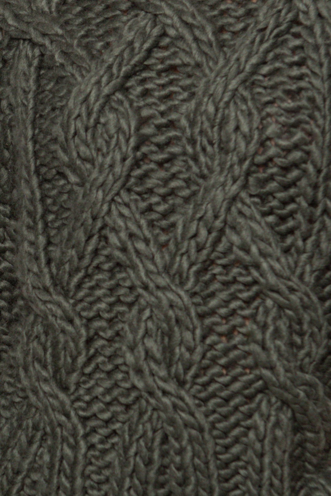 Close-up of a textured fabric with a cable knit pattern in a neutral color.
