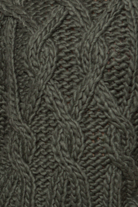 Close-up of a textured fabric with a cable knit pattern in a neutral color.