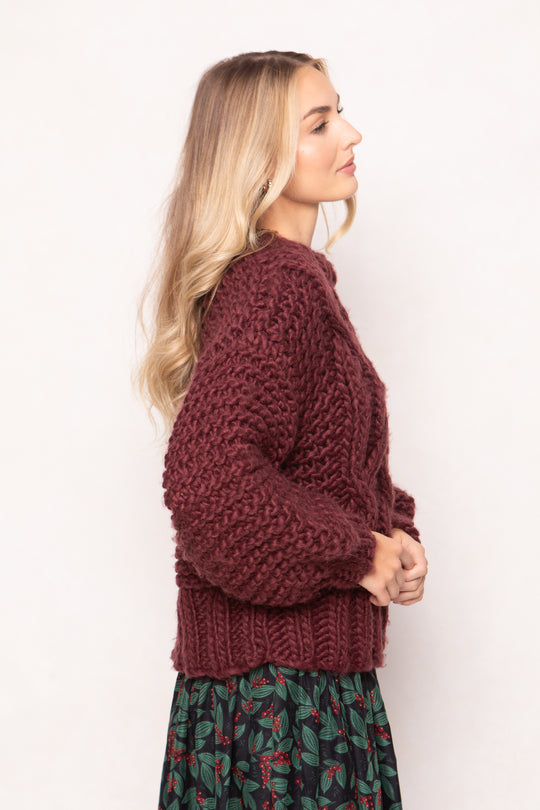 Woman wearing a burgundy knitted sweater against a white background