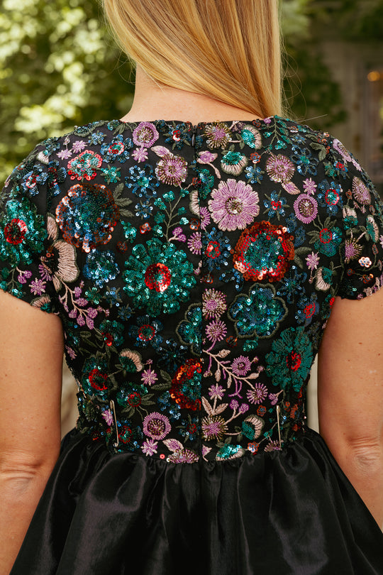 Close-up of a person wearing a dress with floral sequin embellishments.