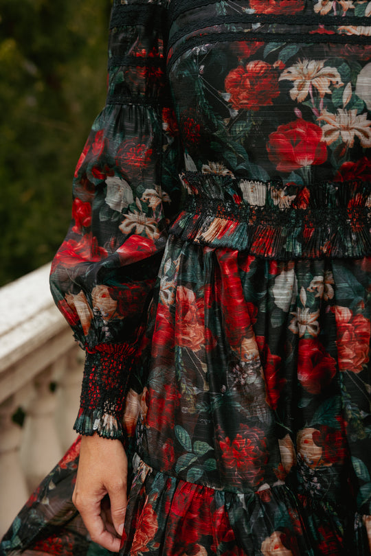Close-up of a person wearing a floral dress with red and green colors.