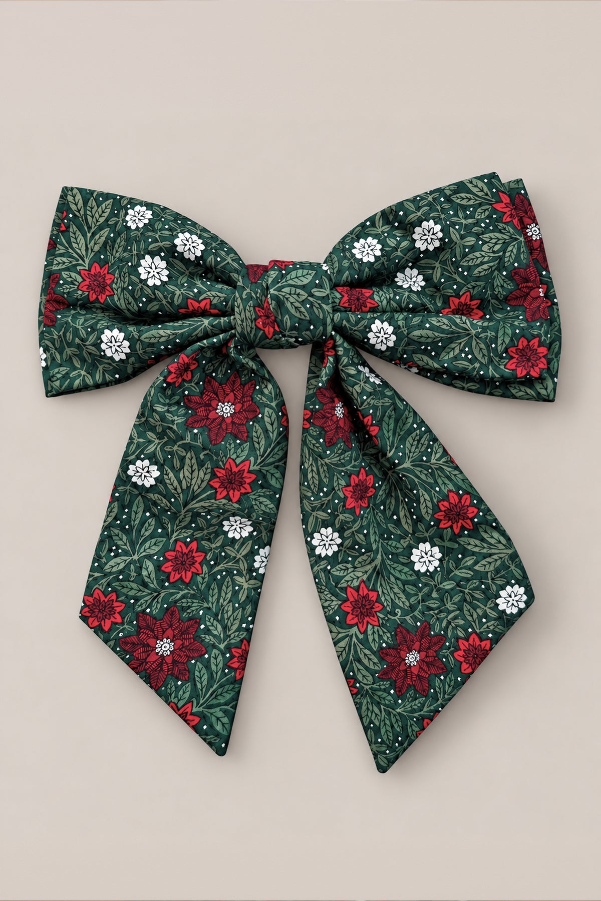 The Hair Bows in Evergreen Merry Ditsy by Ivy City Co feature green fabric adorned with a ditsy floral pattern of red, white, and dark green flowers and leaves. Each bow includes two long tails and is photographed against a plain beige background.
