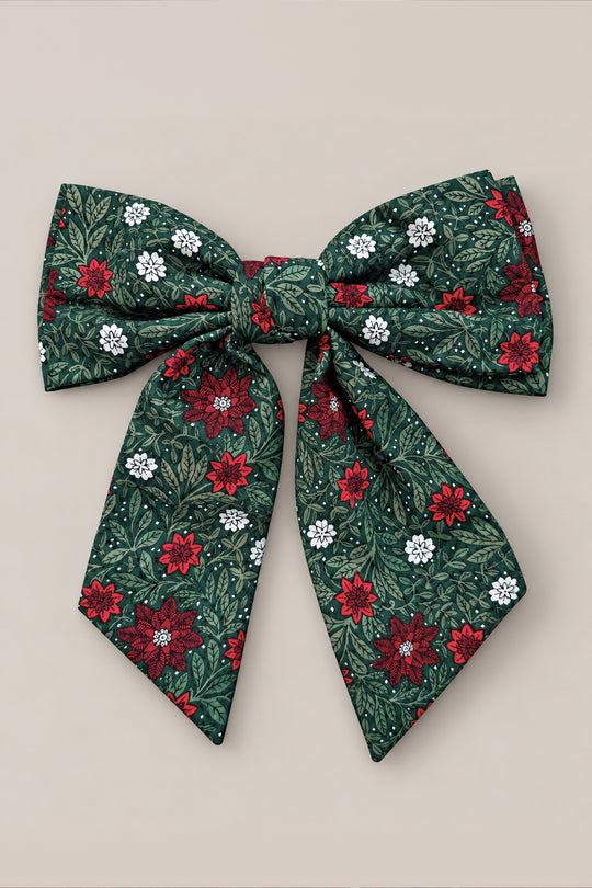 The Hair Bows in Evergreen Merry Ditsy by Ivy City Co feature green fabric adorned with a ditsy floral pattern of red, white, and dark green flowers and leaves. Each bow includes two long tails and is photographed against a plain beige background.