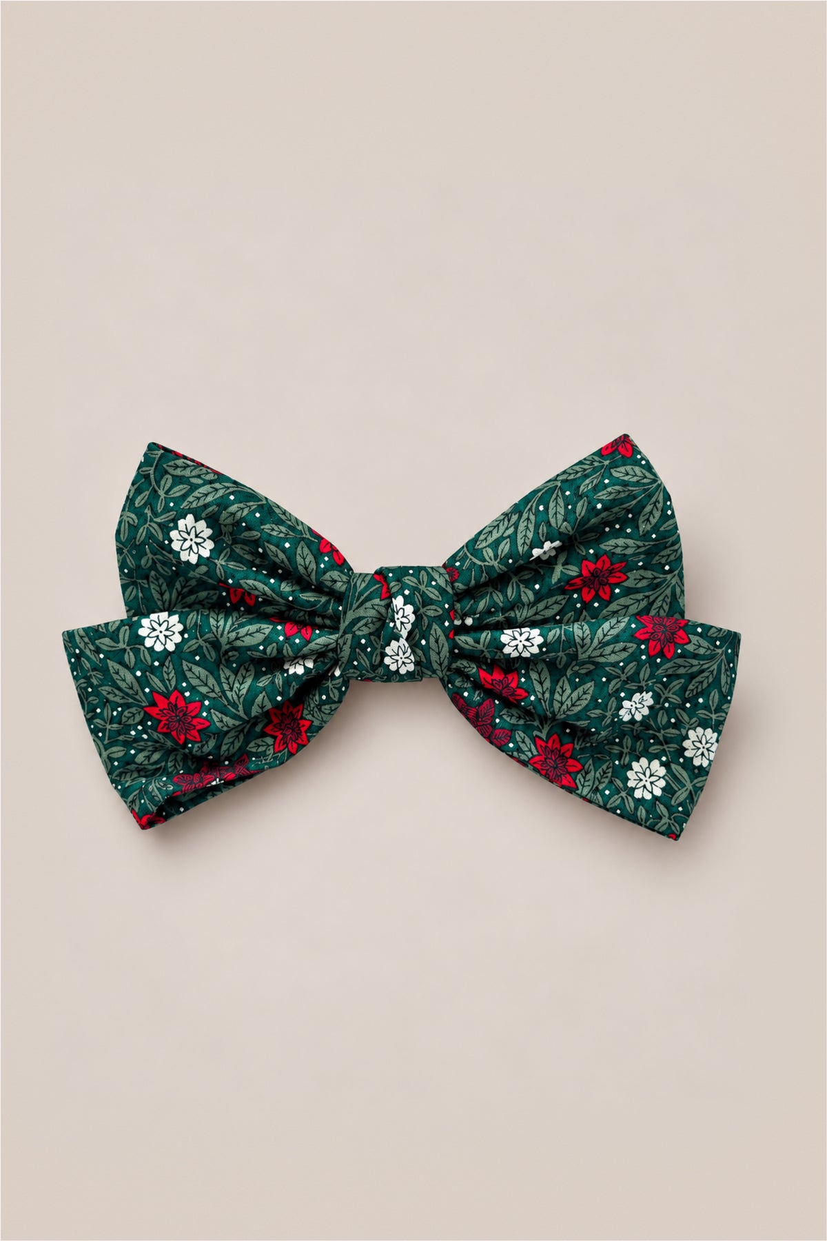 The Hair Bows in Evergreen Merry Ditsy by Ivy City Co feature a green fabric adorned with a ditsy floral pattern of red, white, and light green flowers and leaves, displayed on a light beige background.