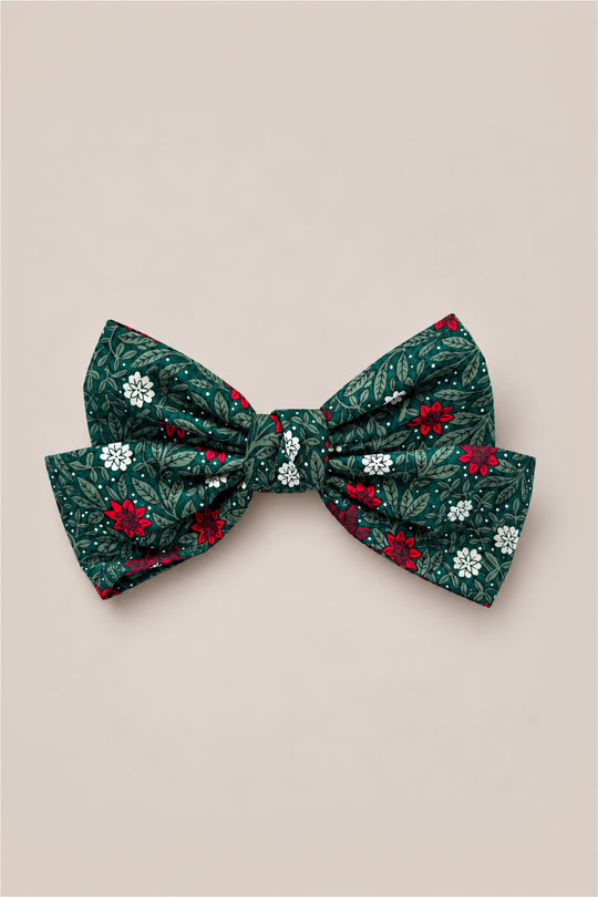 The Hair Bows in Evergreen Merry Ditsy by Ivy City Co feature a green fabric adorned with a ditsy floral pattern of red, white, and light green flowers and leaves, displayed on a light beige background.