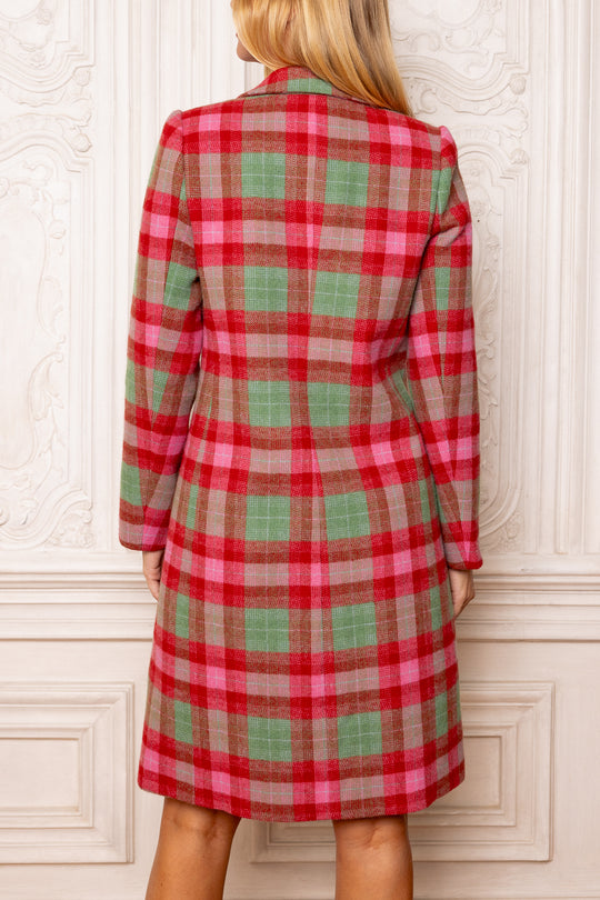 Red and green plaid dress worn by a person against a white wall.