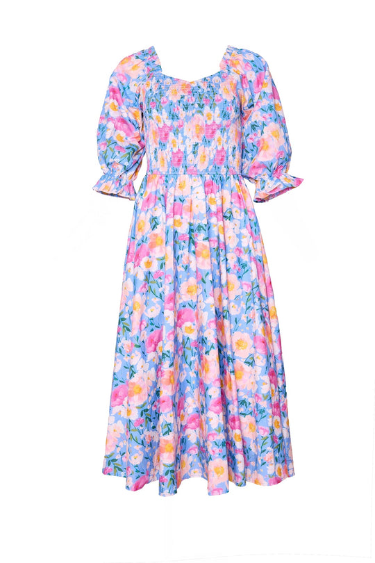 The Teagan Dress in Delia Blue by Ivy City Co is a charming smocked cotton midi dress featuring puffed short sleeves and a smocked bodice, adorned with a multicolored pastel floral print on a light blue background—perfect for any spring occasion.