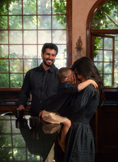 Two parents embrace their child in a kitchen