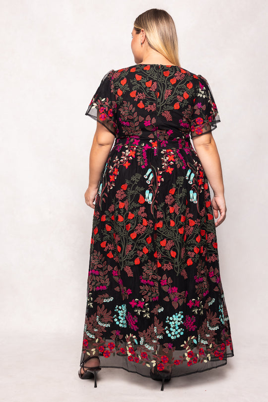 Woman wearing a black floral dress with colorful patterns on a white background