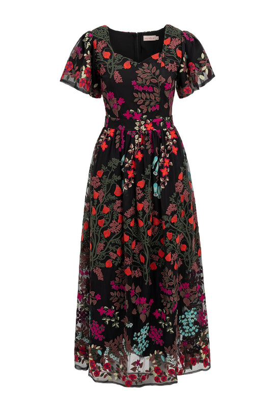 Introducing the Flora Dress in Moonlit Blossom by Ivy City Co—a chic black dress with short sleeves, beautifully embroidered with vibrant red, purple, turquoise, and green blooms. This elegant design showcases a fitted waist, flared skirt, and a tie belt to create a flattering silhouette.