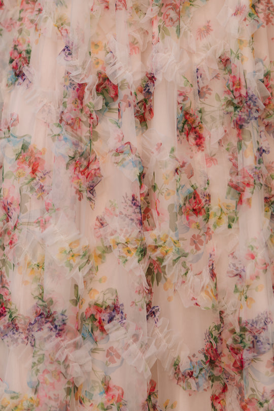 Close-up of the Ivy City Co Florentina Dress in Pink Floral, showcasing delicate ruffled fabric and a vibrant pattern with red, purple, blue, and green flowers.