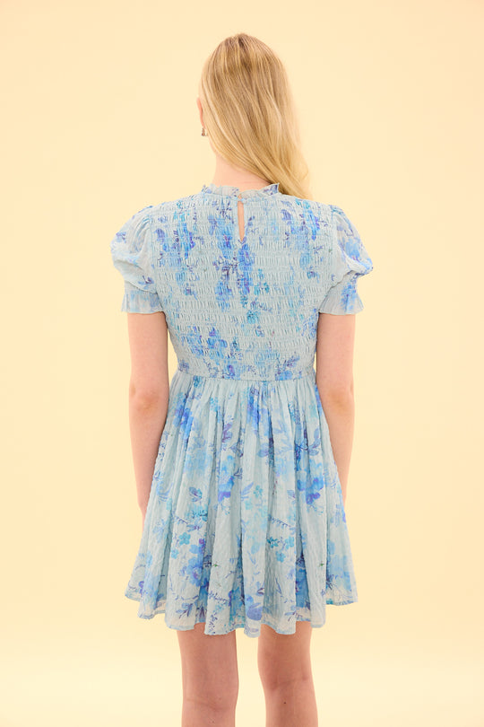Woman wearing a blue floral dress against a beige background
