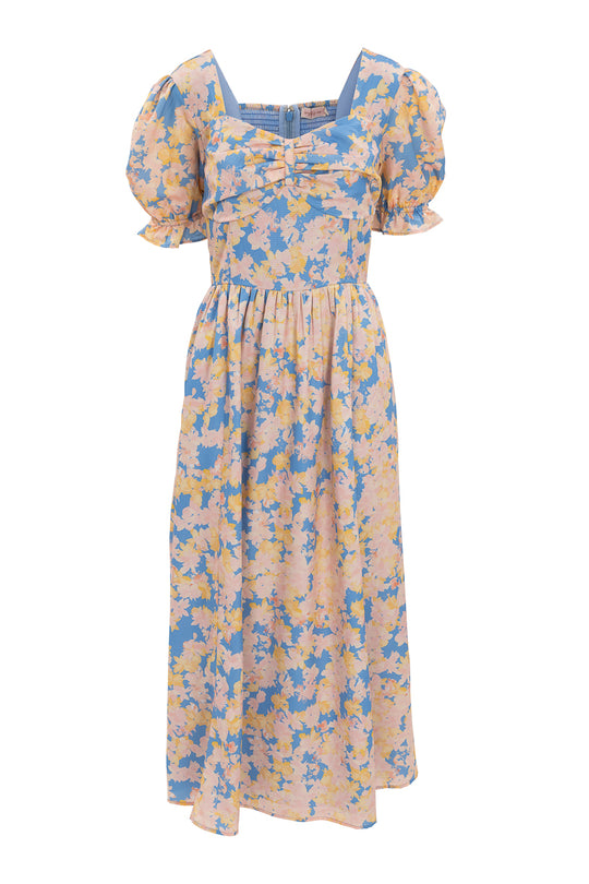 The Mila Dress in Floral by Ivy City Co features short puff sleeves, a square neckline, fitted bodice, and gathered midi skirt. Its pastel blue and peach floral pattern adds a feminine, vintage-inspired touch.