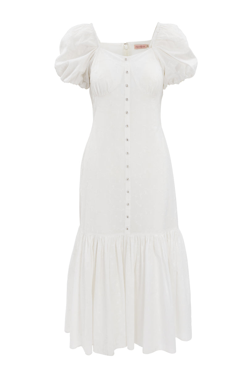 The Liberty Dress in White Eyelet by Ivy City Co features a fit-and-flare silhouette, short puff sleeves, a button-down front, fitted bodice, flared ruffled hem, and an elegant textured eyelet pattern for subtle detail.