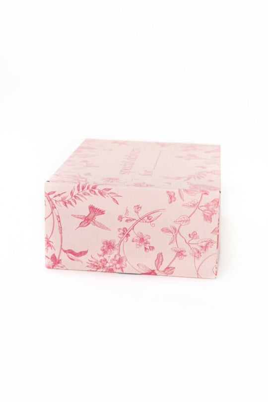 A light pink rectangular Gift Box from Ivy City Co, adorned with darker pink floral and bird patterns and set against a plain white background—this custom packaging makes for a thoughtful gift inspired by Ivy League elegance.