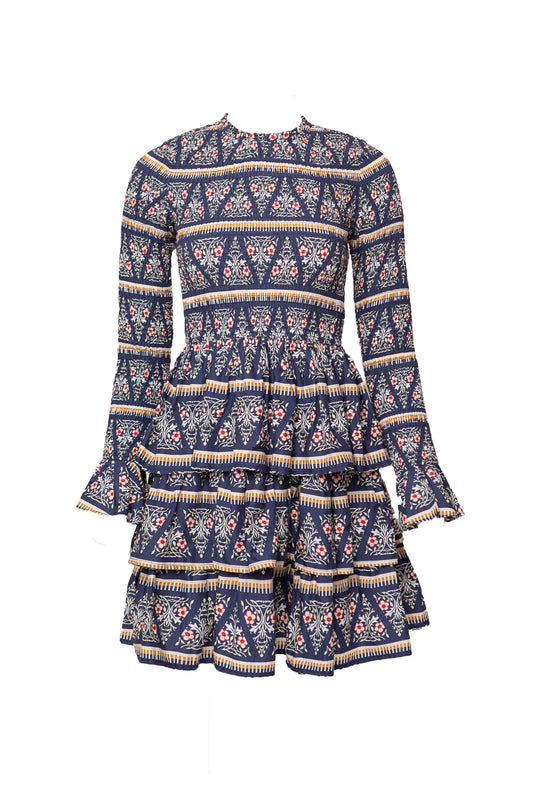 The Greer Dress in Navy Fleur by Ivy City Co features a smocked bodice, high neckline, long sleeves, knee-length tiered ruffle skirt, and intricate navy floral and geometric patterns in white, red, and beige.